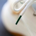 zbliżenie na ochronną plastikową końcówkę sznurowadła jako wizualna metafora telomerów chroniących końce chromosomów